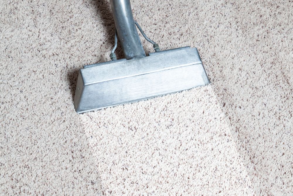 A vacuum cleaner working on a carpet, showcasing the services of a carpet restoration company in Springfield, IL.