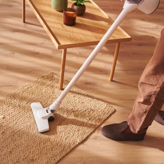 A person operates a vacuum on a rug, highlighting a carpet cleaning service in Springfield, IL.